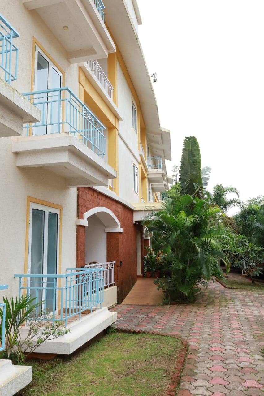 Anjuna Abode 1 — building exterior with blue balconies and tropical garden