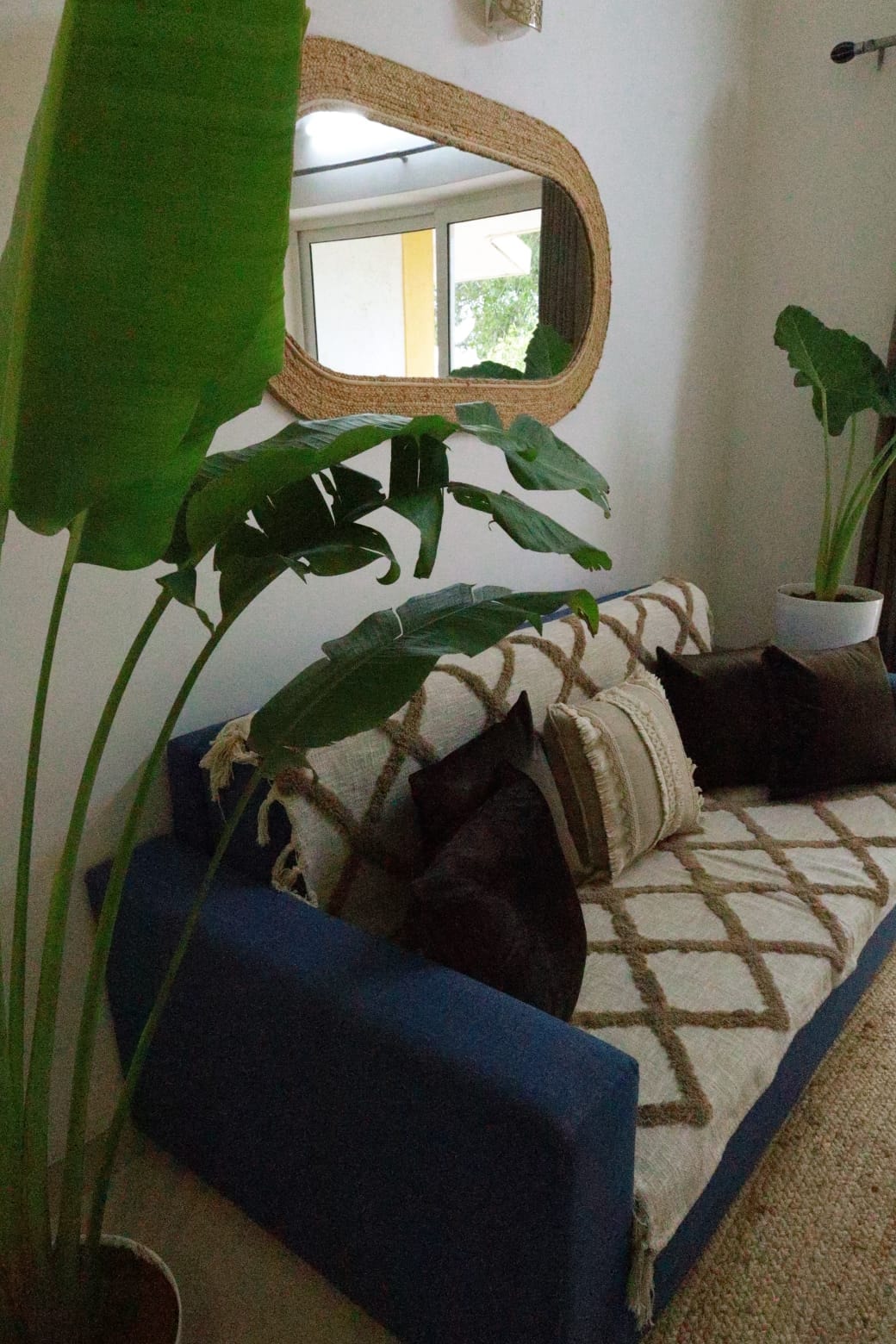Anjuna Abode 2 — sofa with banana leaf plants and rattan mirror